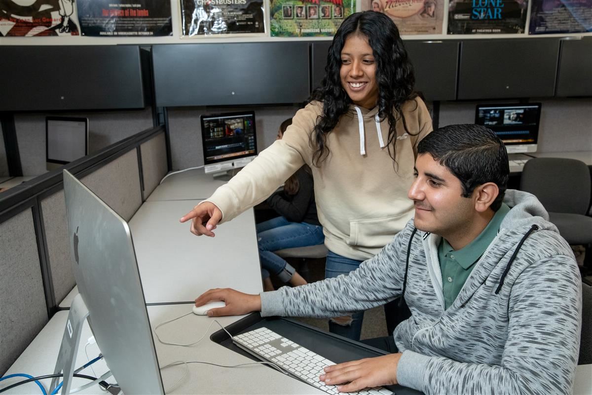 Two students collaborating at an Apple computer 