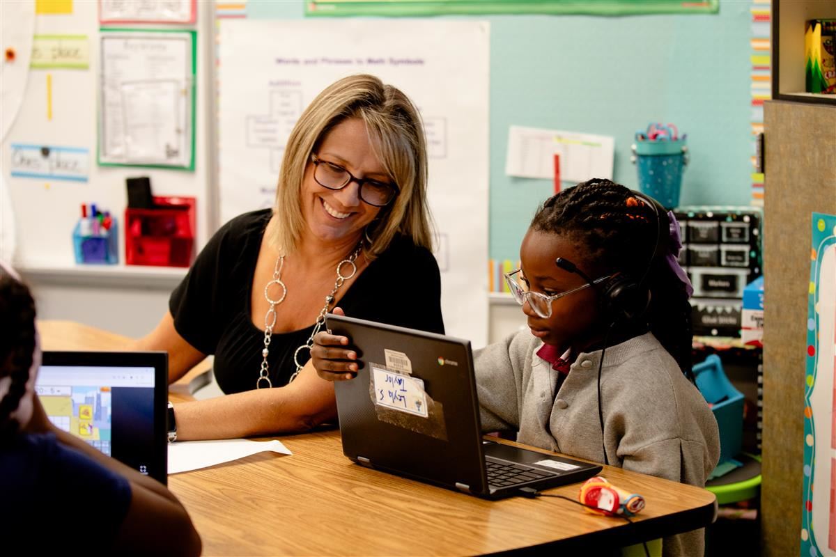 Teacher with student at a laptop 