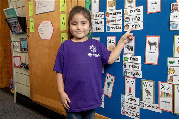 Elementary age student points to the word nino on a Spanish word wall 