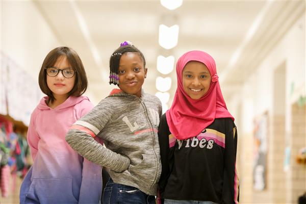 Three elementary students standing in hallway 