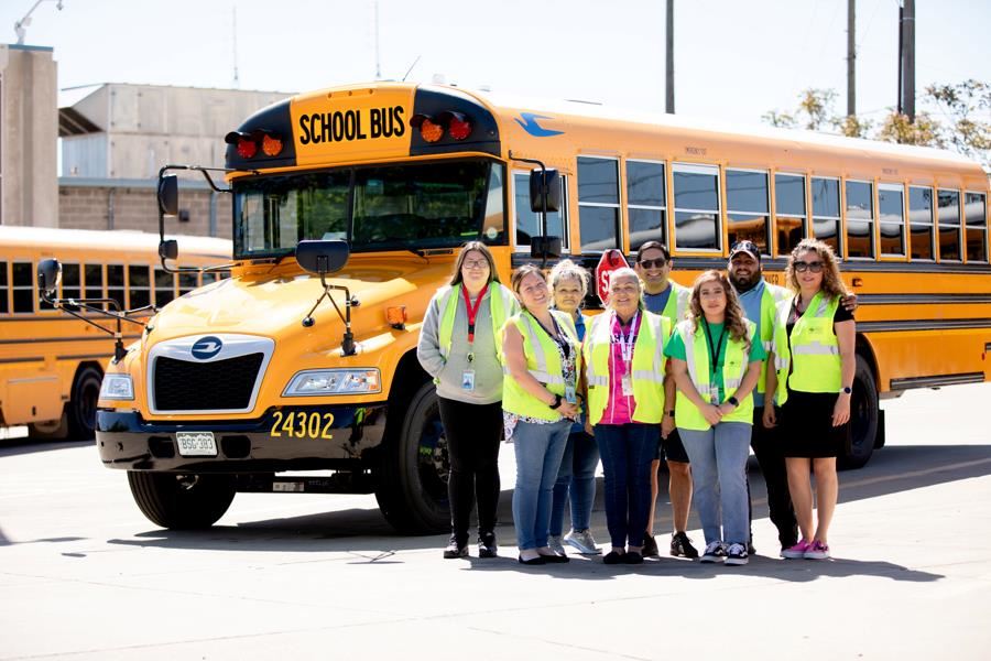 Bus drivers in front of bus smiling 