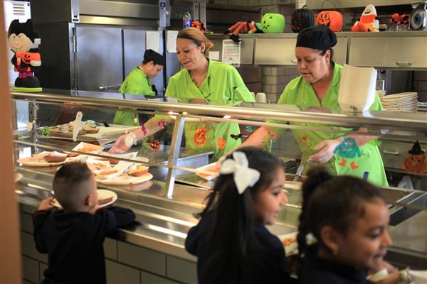 Cafeteria staff serving children food